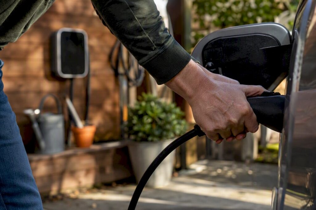 Hands plugging in EV charger at home