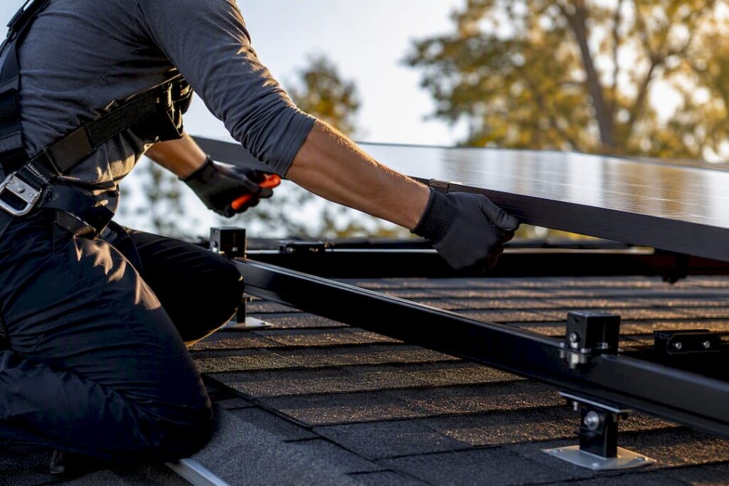 Technician lowering solar panel onto roof racking