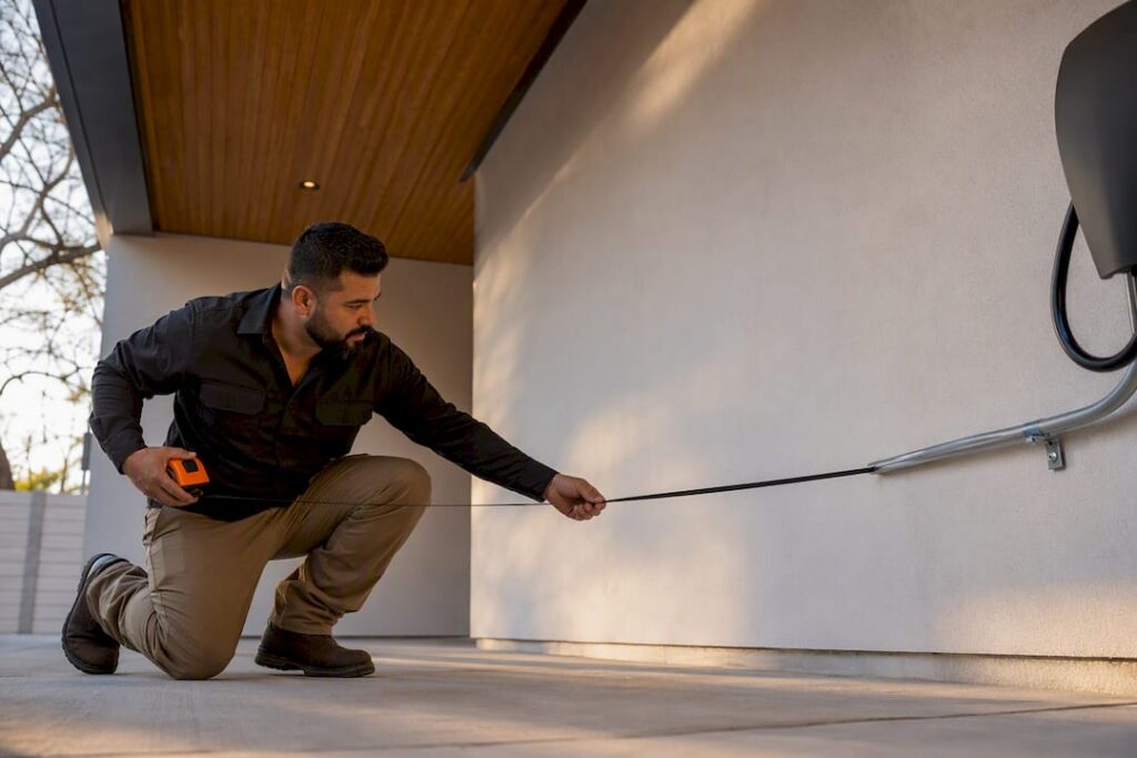 Electrician measuring EV charger cable reach